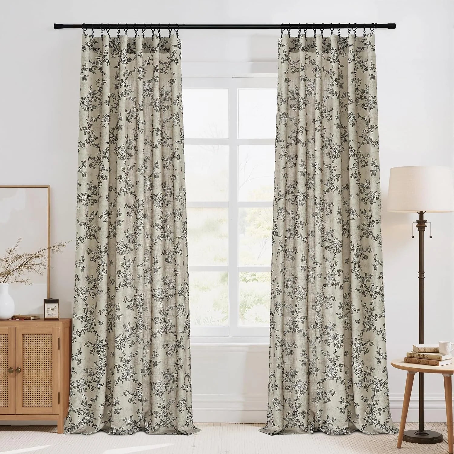 Beige linen-look curtains with black botanical print on rings in a bright room