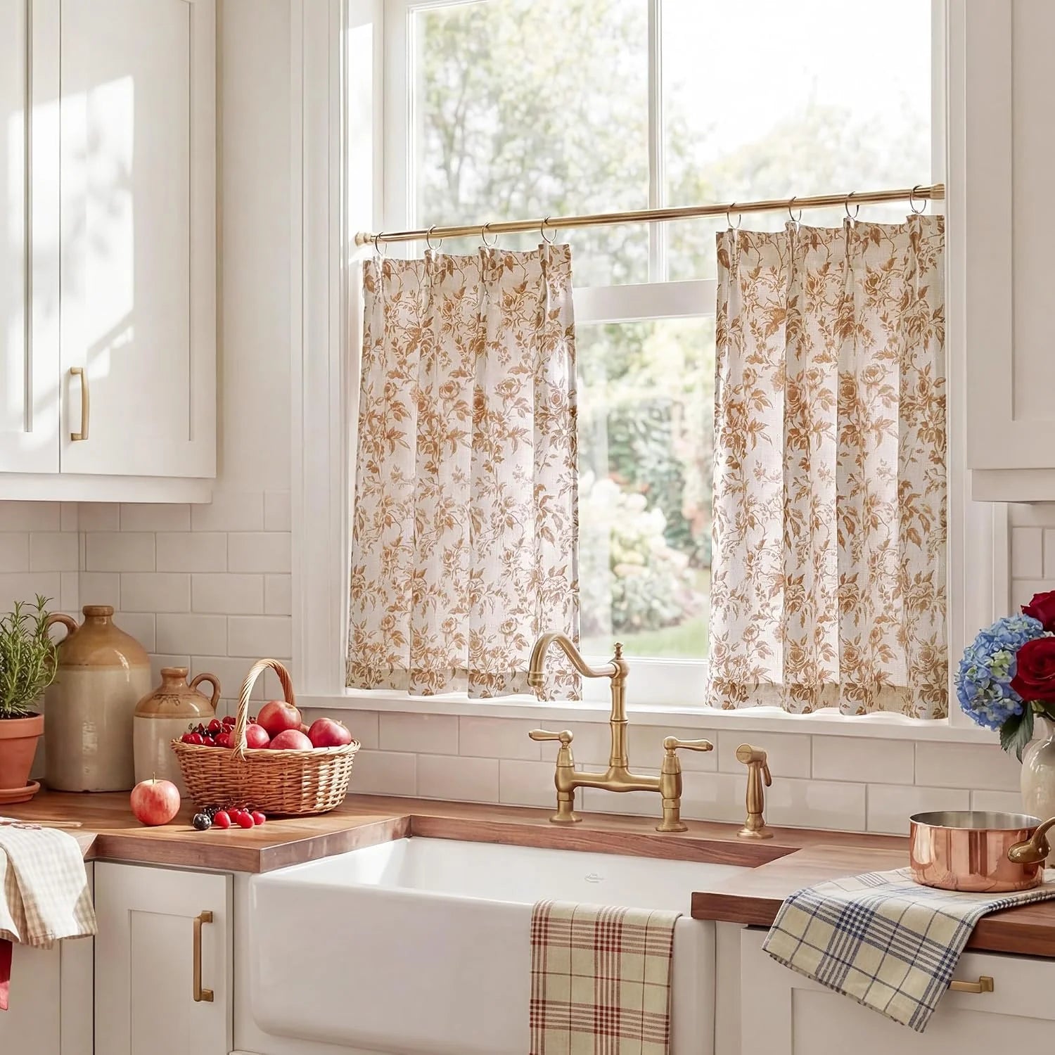 Beige floral cafe curtains hanging on brass rod above a bright farmhouse kitchen sink