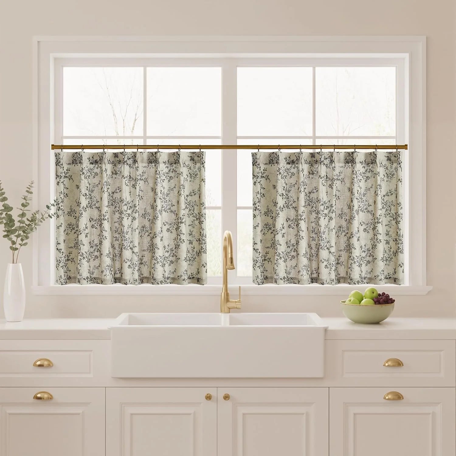 Beige floral cafe curtains on a brass rod above a white farmhouse kitchen sink