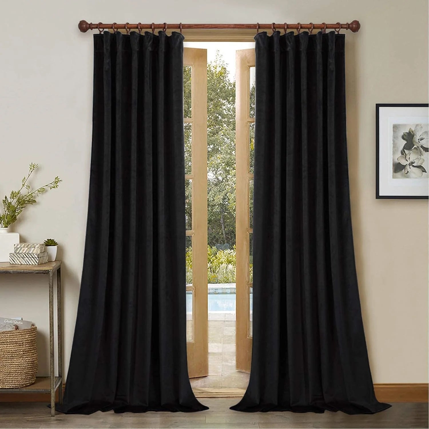 Black velvet curtains hanging on a wooden rod in a bright neutral living room