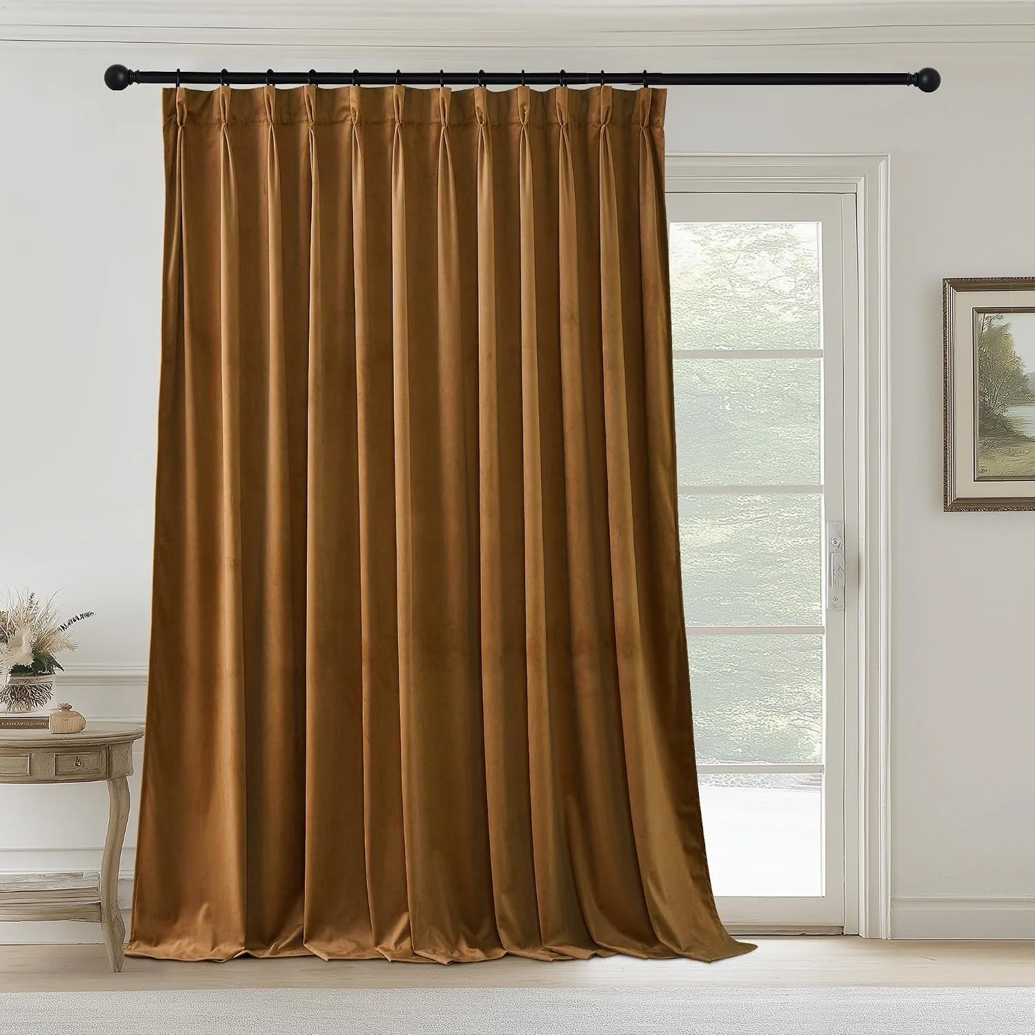 Caramel velvet pinched pleat curtain panel hanging on a black rod by a glass door