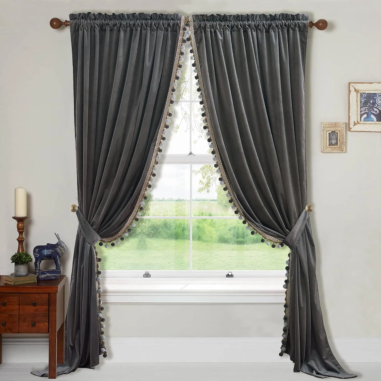 Charcoal velvet curtains with pom-pom trim and tiebacks on a bright window