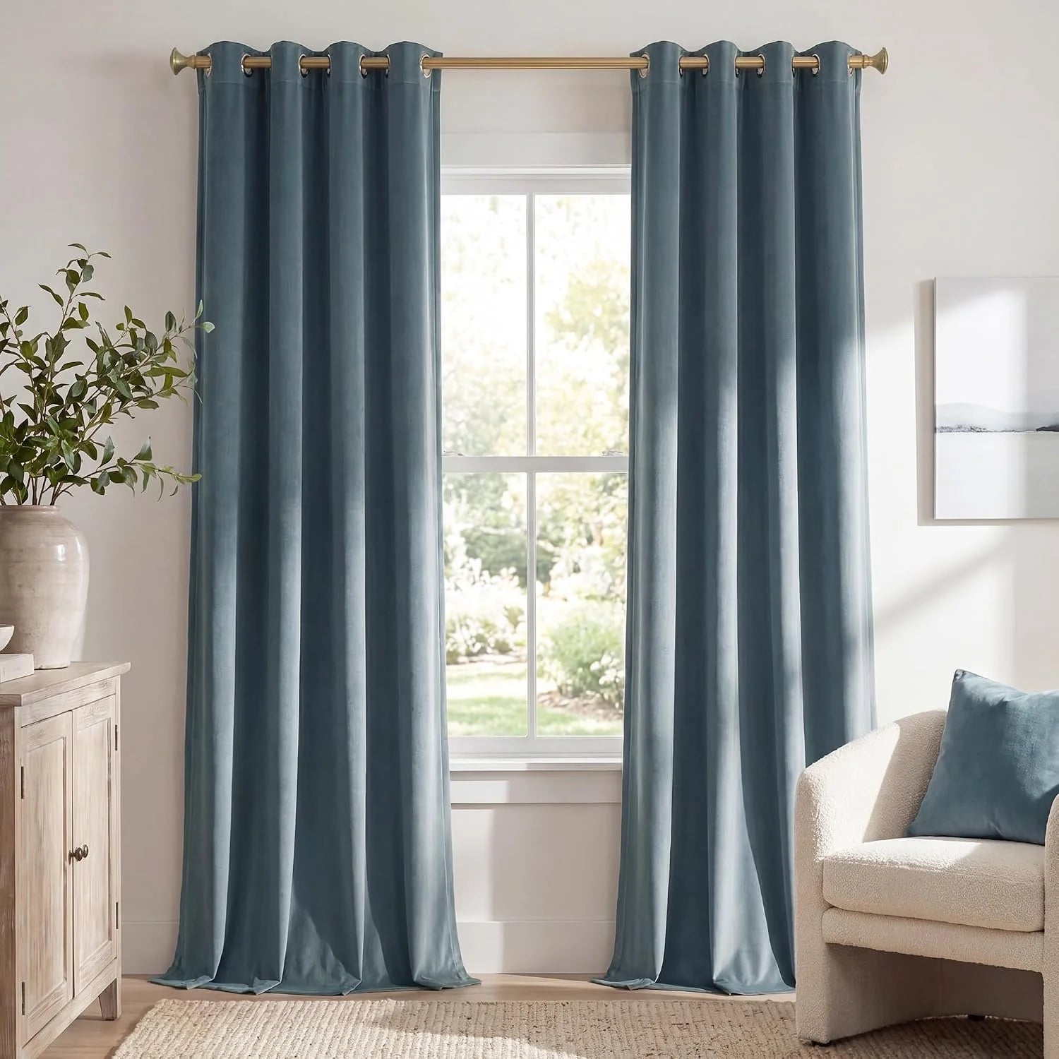 Dusty blue velvet grommet curtains hanging in a bright modern living room window