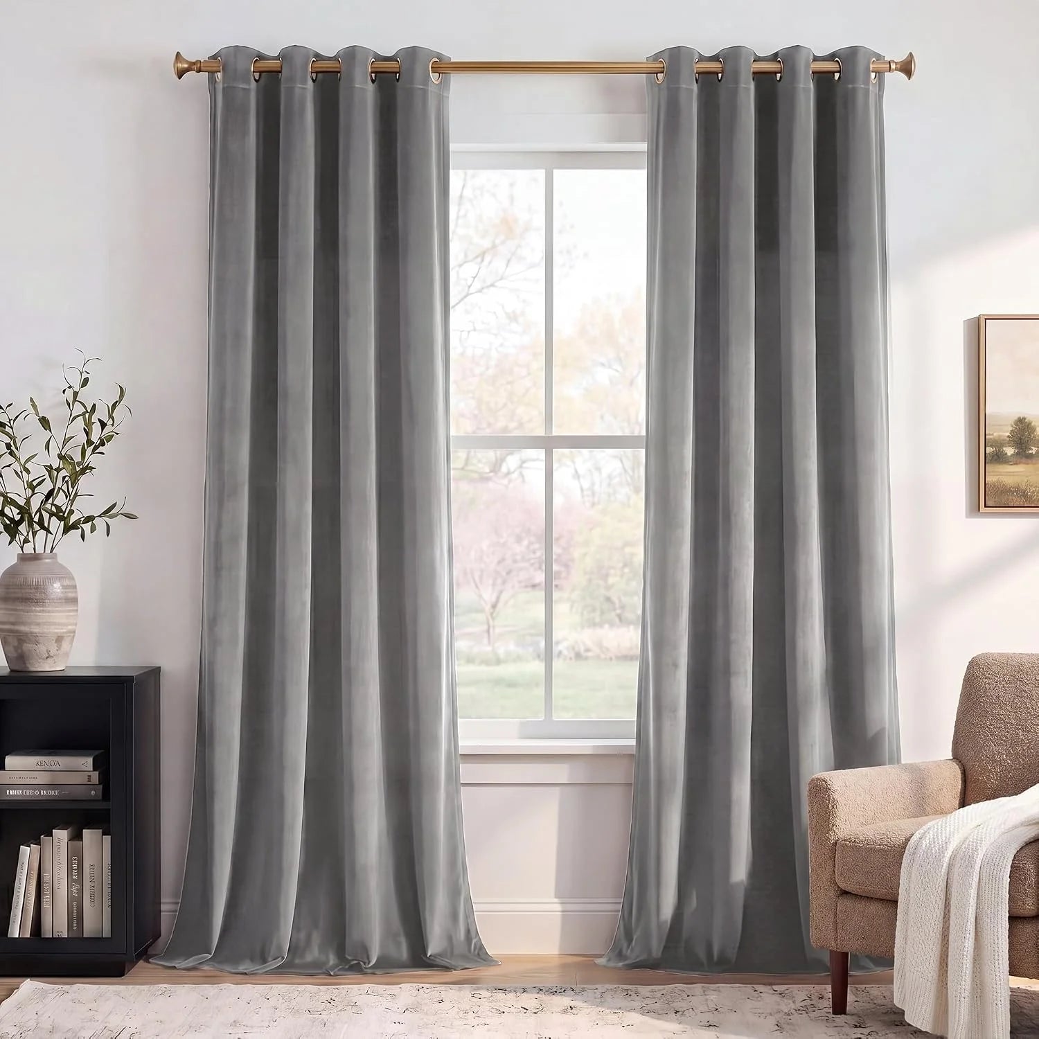 Soft gray velvet grommet curtains hanging on a brass rod in a bright living room