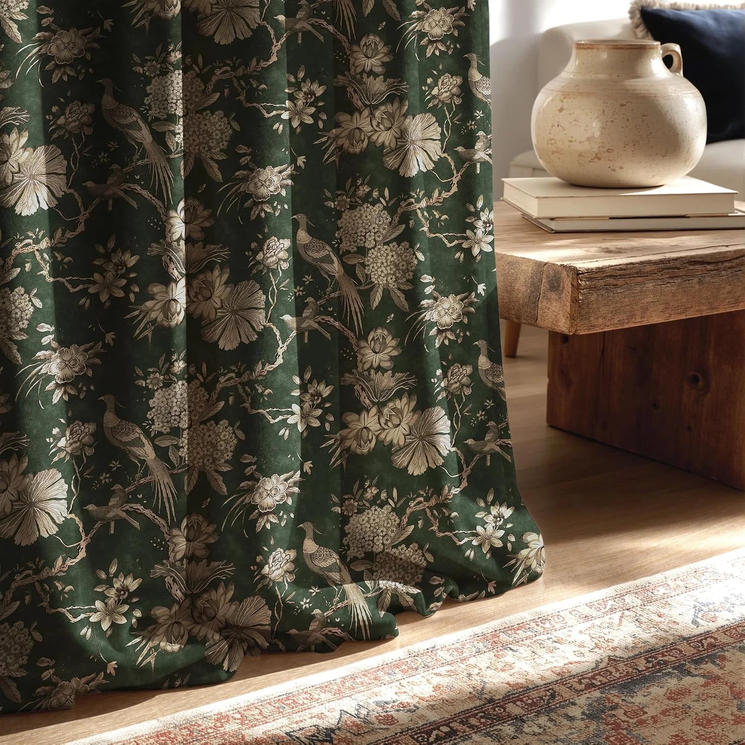 Dark green curtain with beige floral and bird print beside a rustic wood table