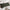 Dark green floral lumbar throw pillow on a white bed with layered pillows