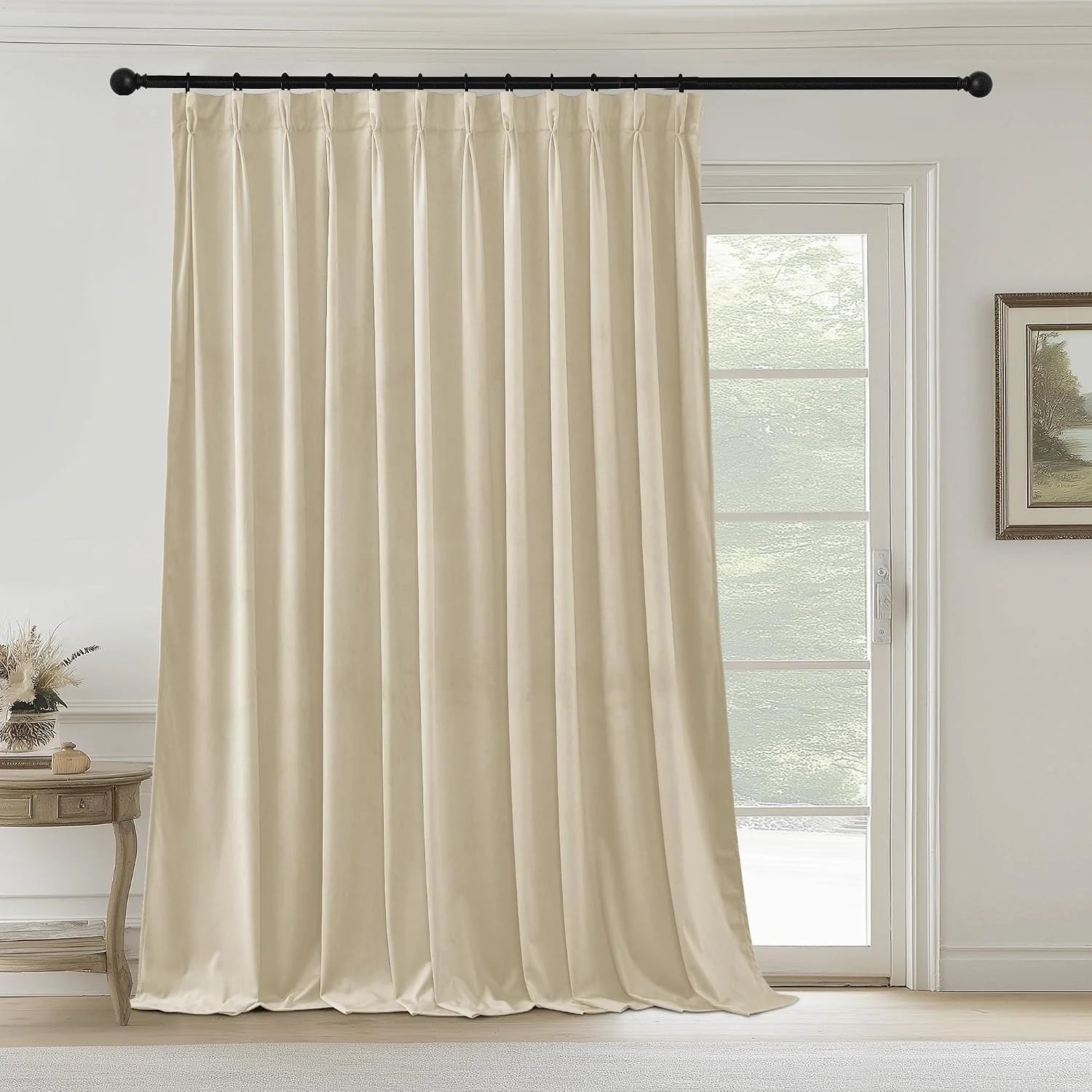 Ivory pinched pleat curtain panel hanging on a black rod beside a glass door
