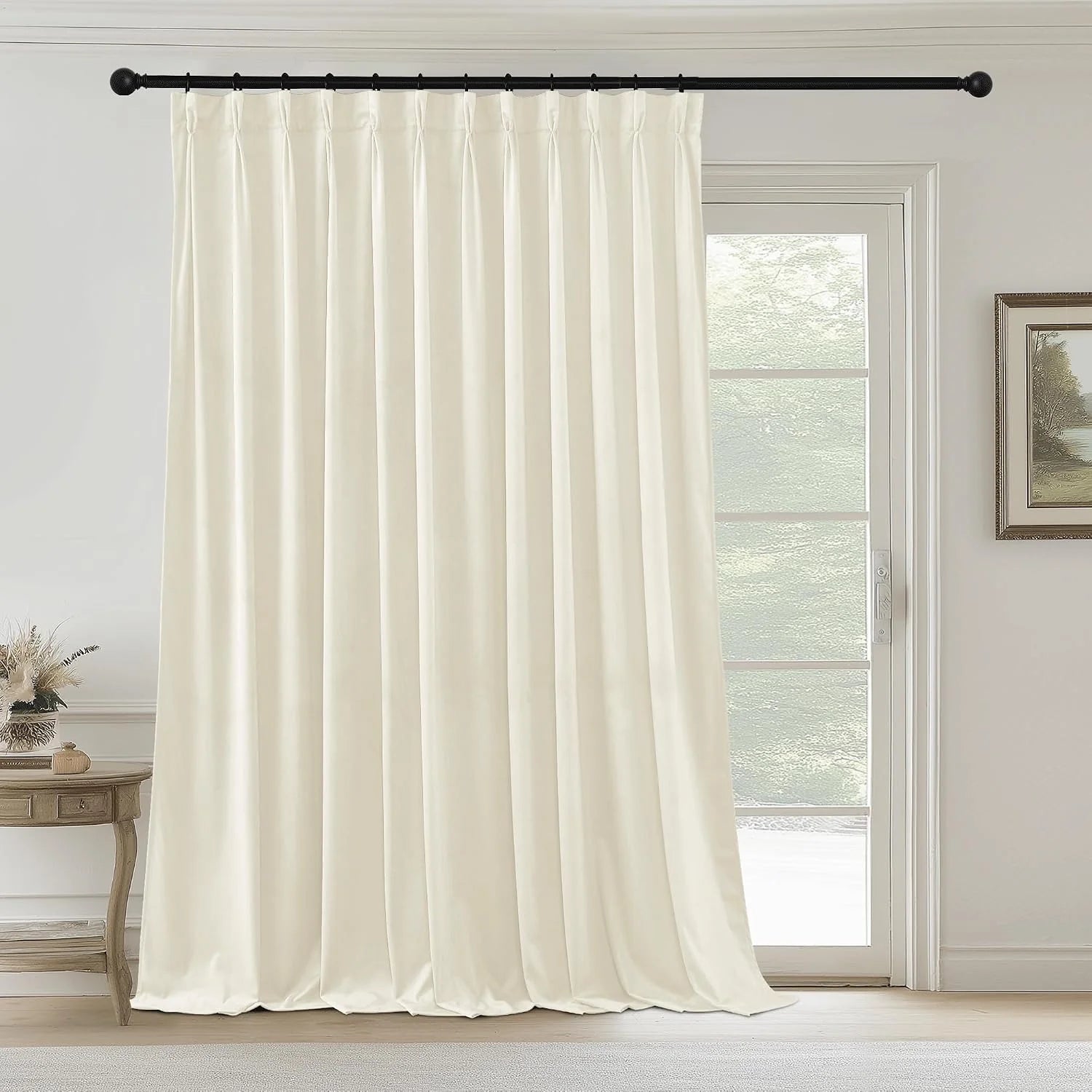 Ivory pinched pleat curtain panel on a black rod beside a glass patio door