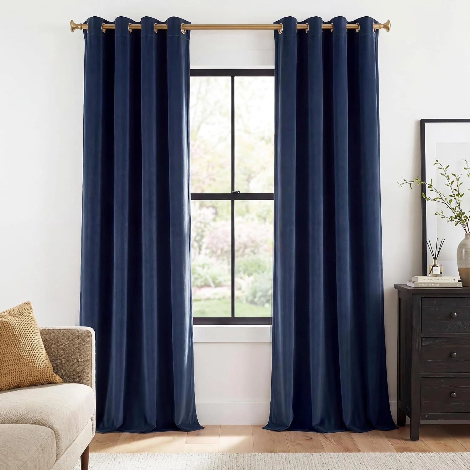 Navy velvet grommet curtains on a brass rod in a bright modern living room
