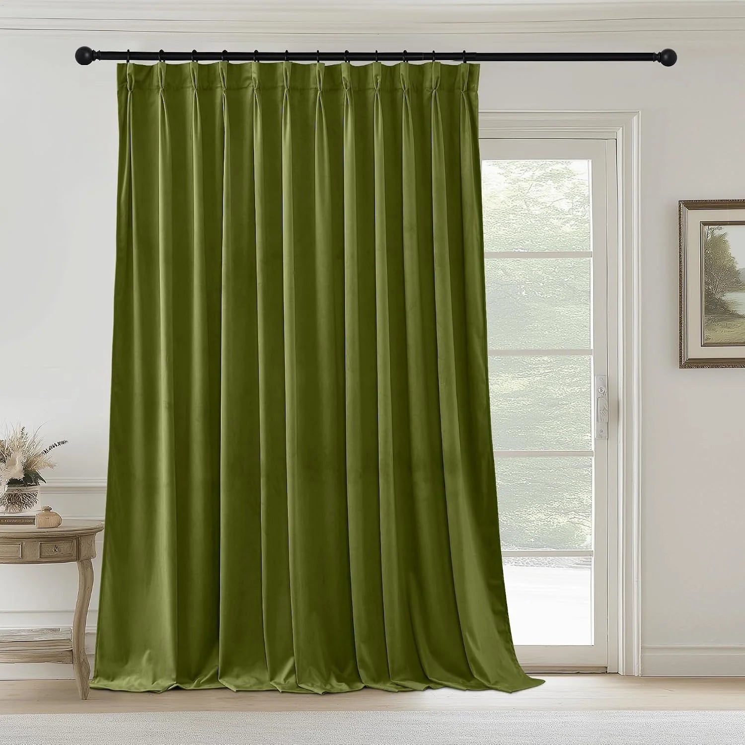 Olive green velvet pinch pleat curtain panel on a black rod in a bright neutral room