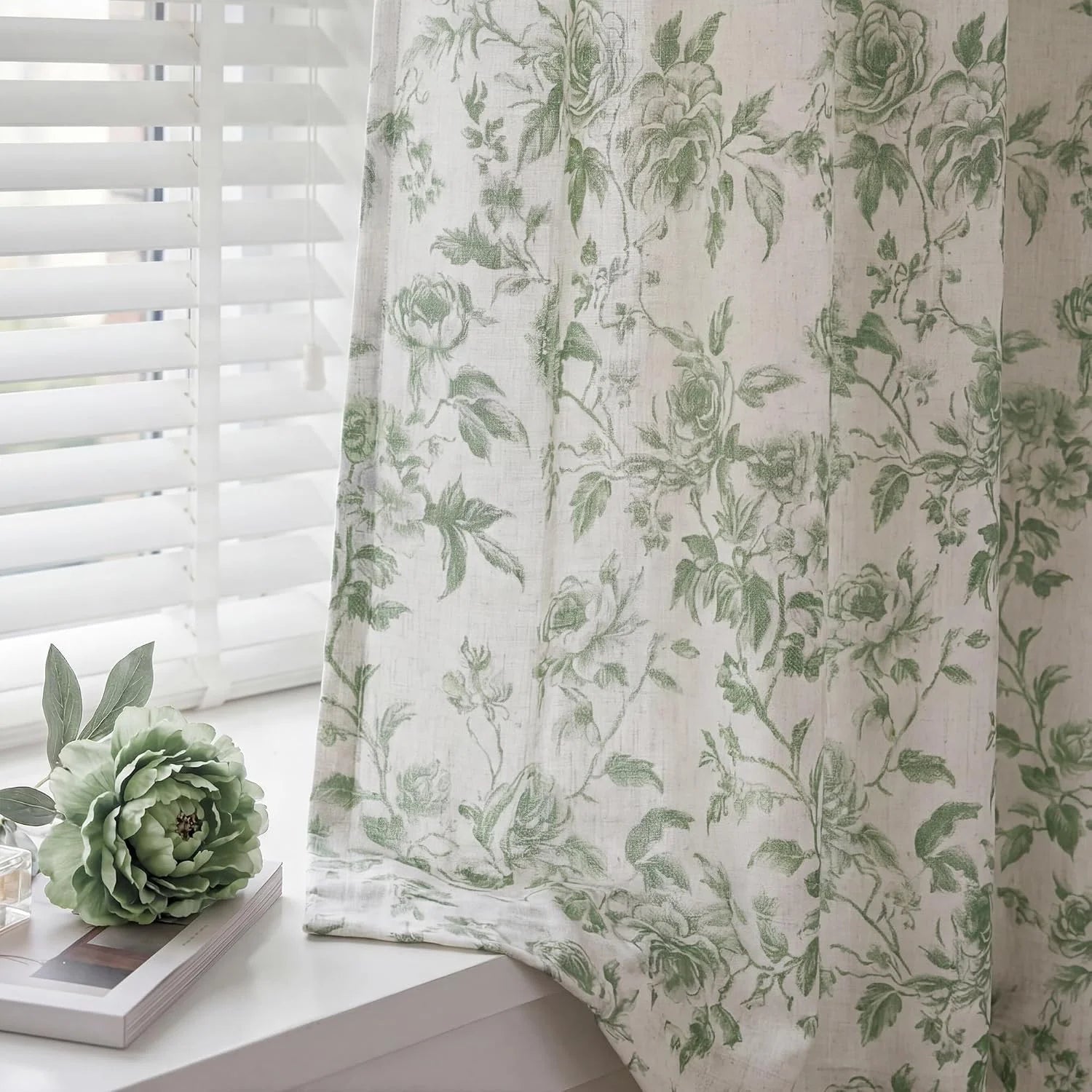Sage green floral sheer linen curtain beside white blinds on a bright window