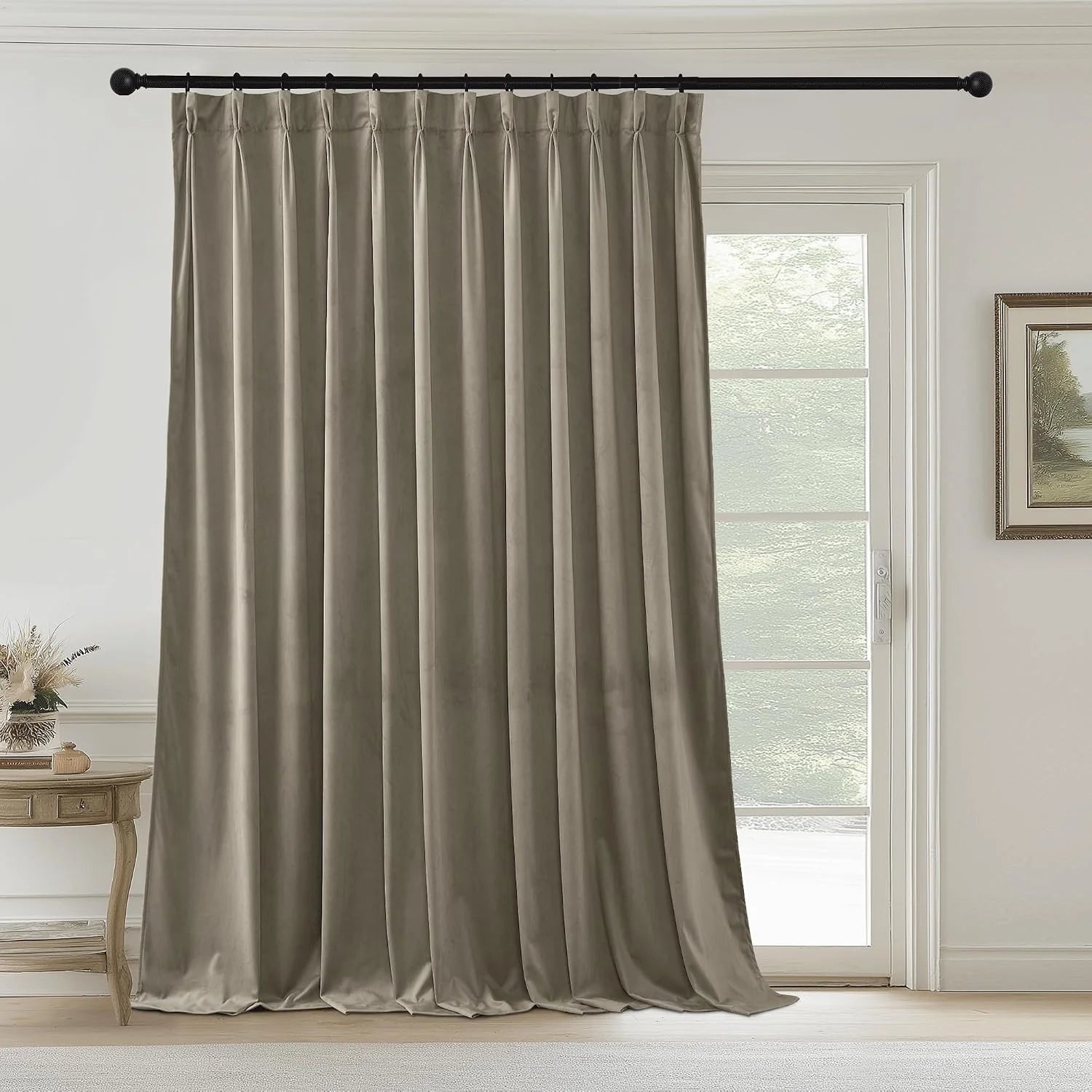 Taupe velvet pinch pleat curtain panel hanging on a black rod beside a glass door