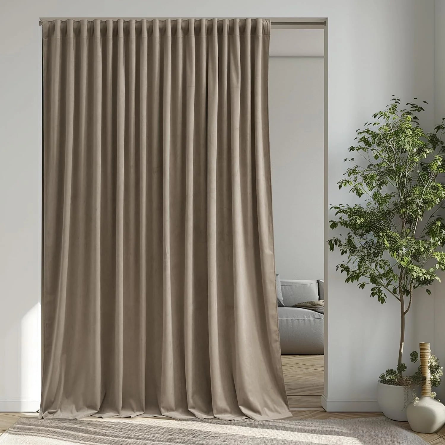 Taupe velvet pinched pleat curtain hanging in a bright modern room with potted tree
